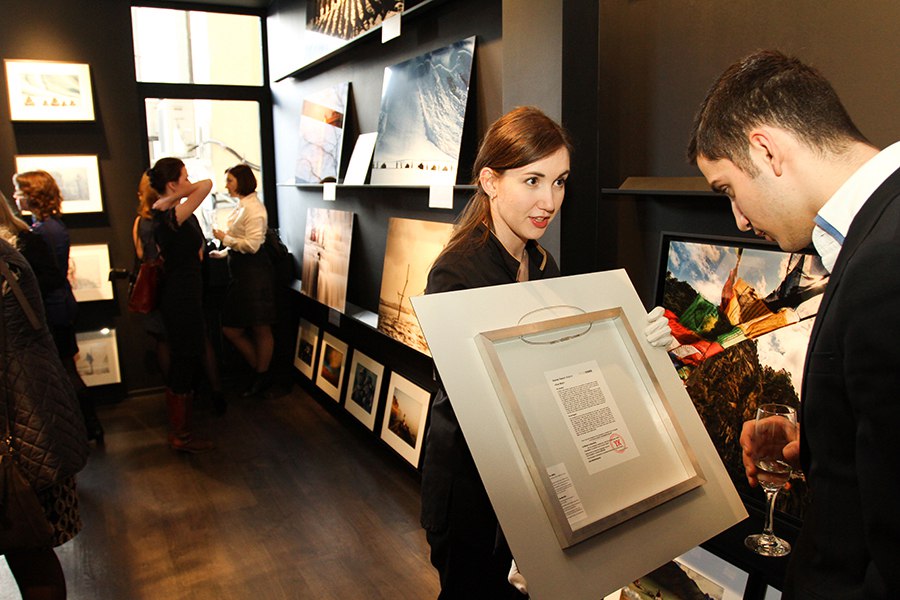 Сотрудник международной галлереи, авторской фотографии Yellowcorner, демонстрирует информацию на обороте фотоработы, на открытии галереи в Санкт-Петербурге