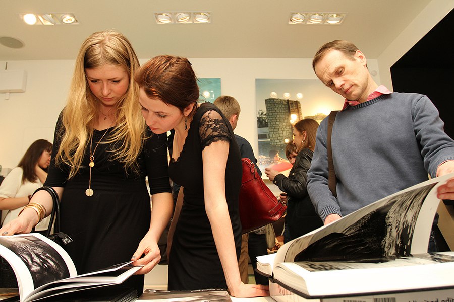 Гости рассматривают фотоальбомы с коллекционными фотографиями продающиеся в галерее Yellowkorner